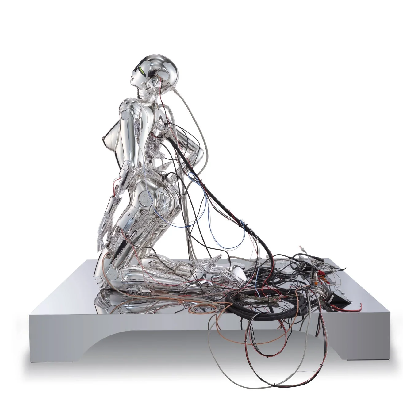 白い背景に、ひざまずくポーズのメタリックなヒューマノイド型ロボットの彫刻が描かれています。その背中からは多数のケーブルが伸び、未来的な雰囲気と芸術性を兼ね備えた作品です。