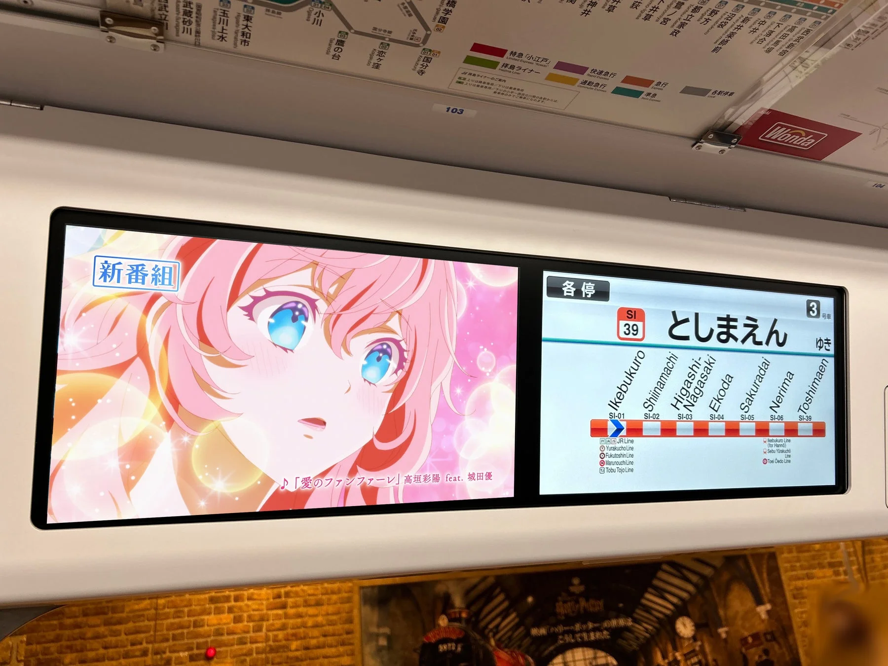 電車内のLCDディスプレイに表示されたアニメキャラクターと楽曲情報