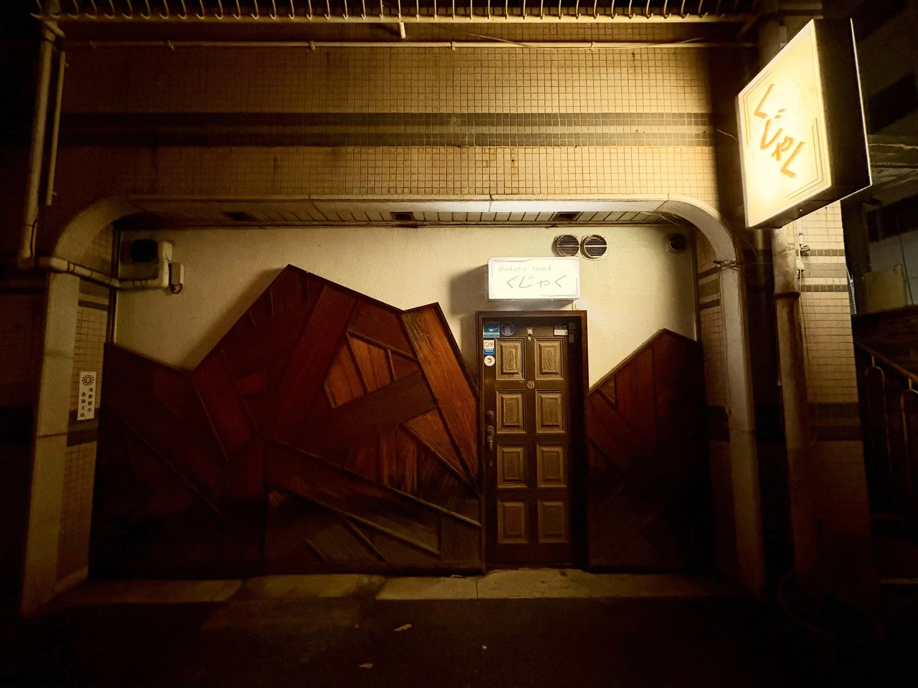 夜の建物の入り口を捉えた「Izakaya Snack くじゃく」