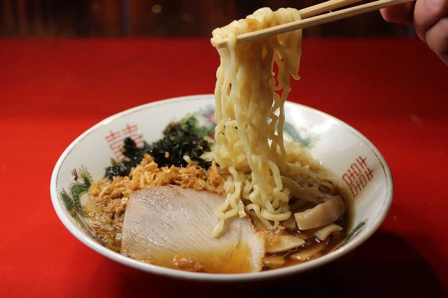 箸で持ち上げられた麺が印象的なラーメンのクローズアップ画像
