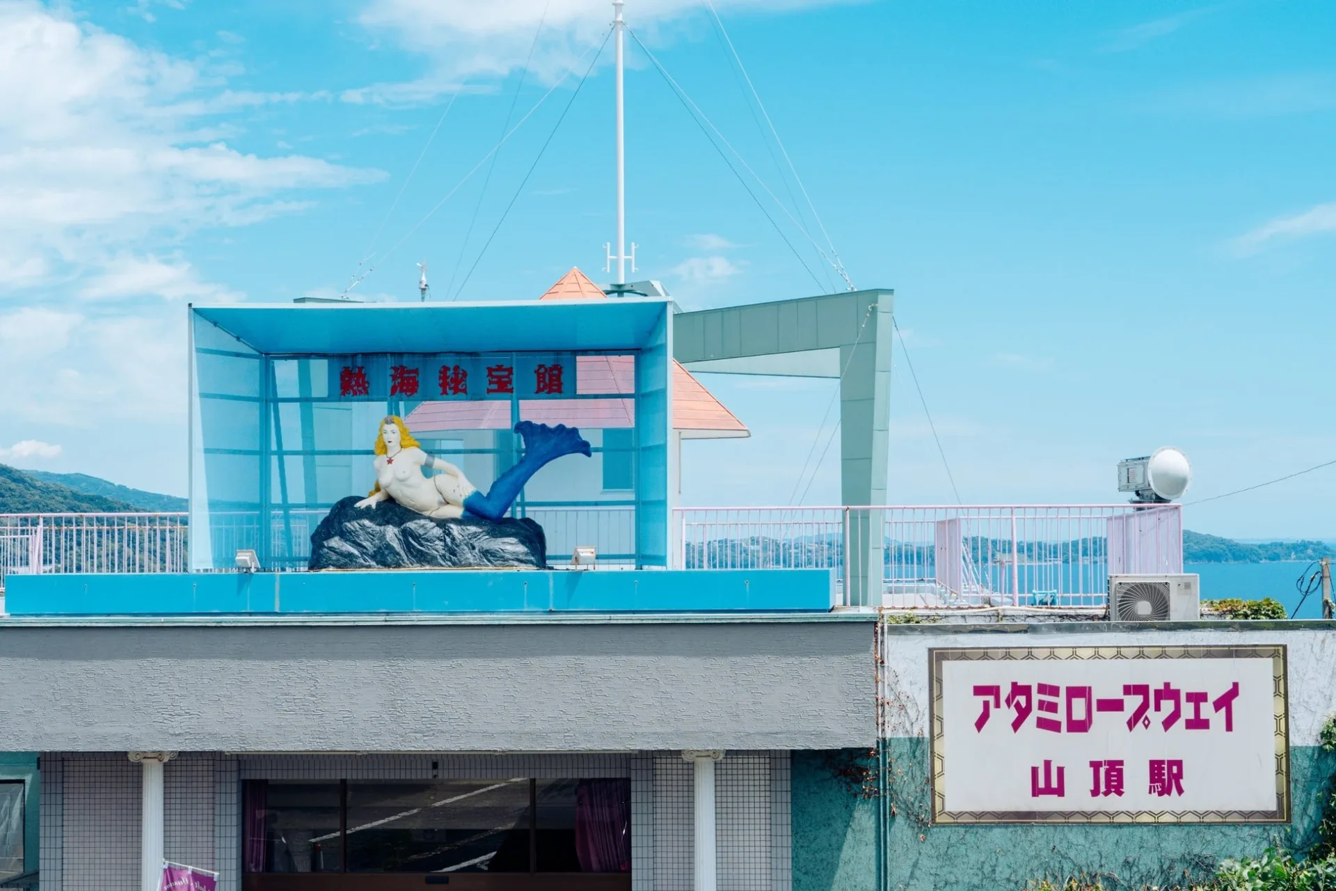 青空の下、熱海秘宝館の建物と屋上の人魚の像