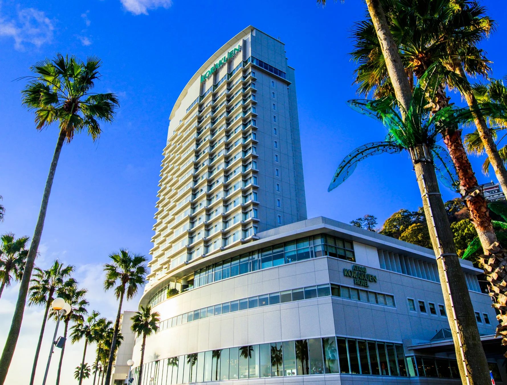 青い空とヤシの木に囲まれたモダンな高層ホテル「ATAMI KORAKUEN HOTEL」