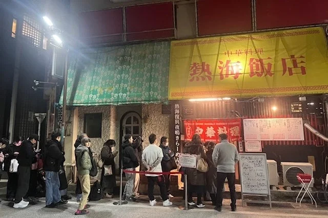 夜の「熱海飯店」の前に多くの人が行列を作っている